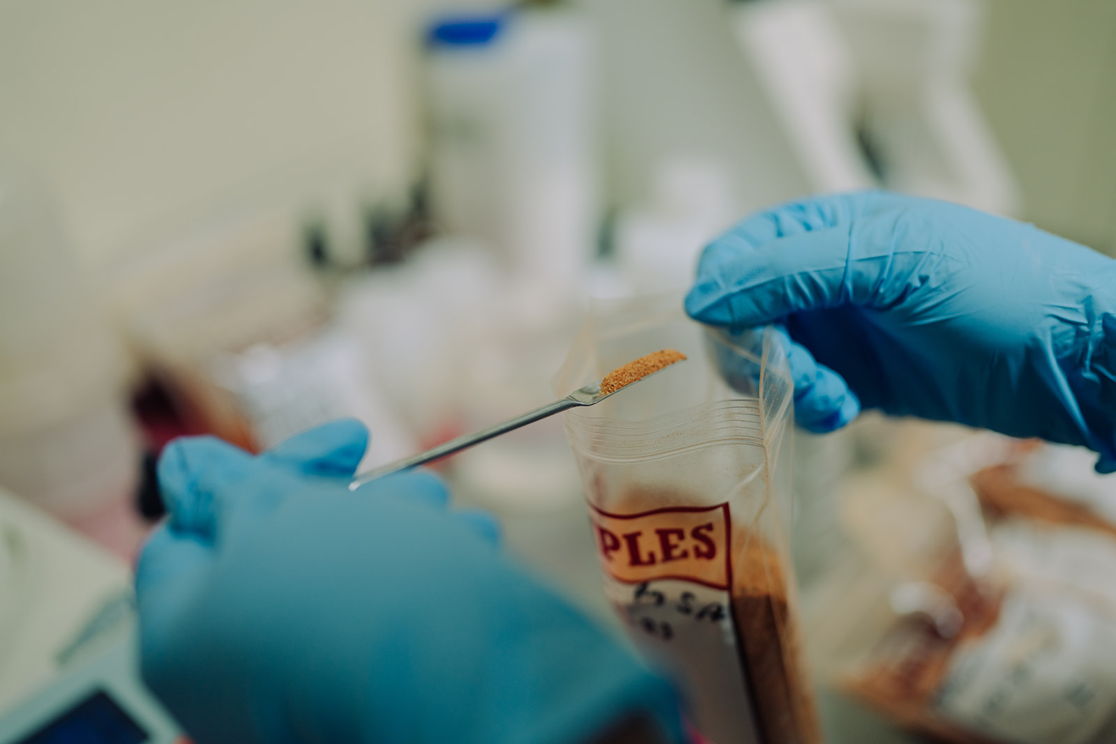 Gloved hands using a pipette for sample testing in the QC lab at TEKPAK's Marion, AL facility