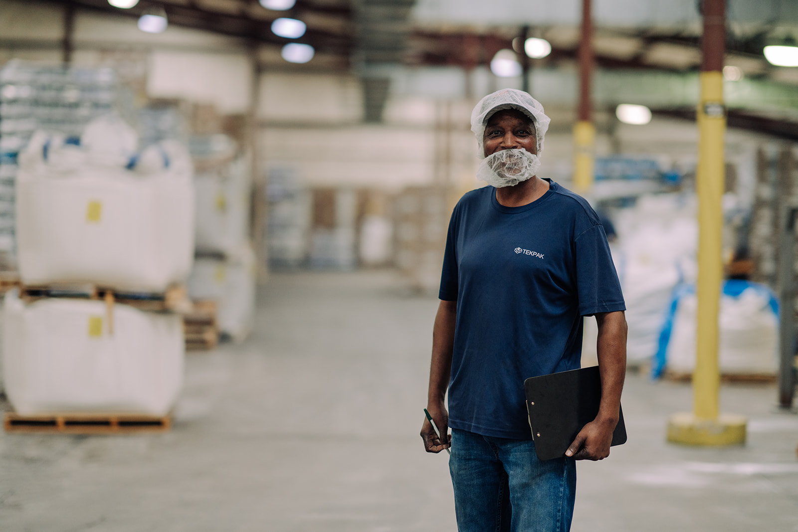 Worker portrait with warehouse pallets in background at TEKPAK's Marion, AL facility